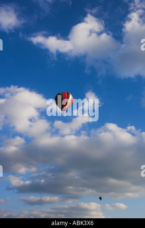 Rot gelb und Purpur Heißluftballon vor einem tiefblauen Himmel mit Wolken Stockfoto