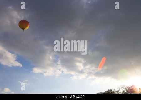 Fernen rot und gelb hot air Ballon steigt oben links in Richtung graue Wolken Stockfoto