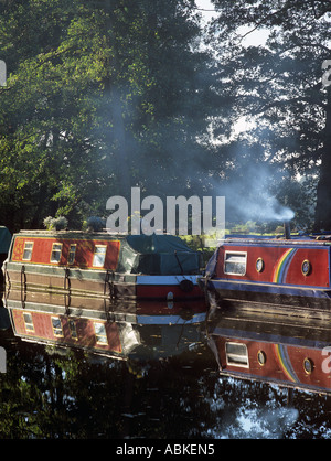 Vertäut schmalen Kanalboote auf Wey Navigation mit Rauch steigt auf kalten Winter am frühen Morgen Sutton grün Surrey England UK Stockfoto