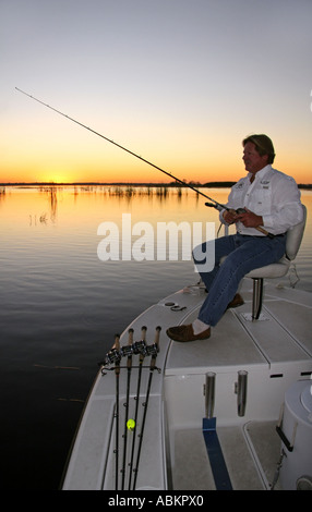 Foto der Mann mittleren Alters, Angeln vom Boot auf den Sonnenaufgang am großen See in Zentral-Florida Stockfoto