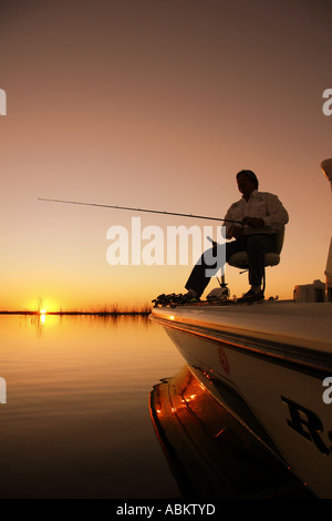 Foto der Mann mittleren Alters, Angeln vom Boot auf den Sonnenaufgang am großen See in Zentral-Florida Stockfoto