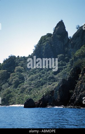 Vulkangestein steigt aus dem Meer, mit üppiger Vegetation bedeckt Stockfoto