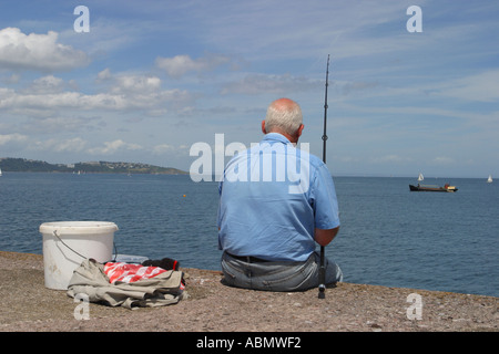 Mittlere Alter Mann Angeln allein von der Hafenmauer in Brixham Devon Stockfoto