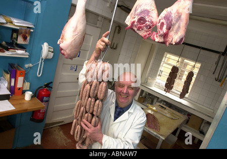 Metzger enthält eine Zeichenfolge von Würsten hängen von einem Haken in seinem Shop UK Stockfoto