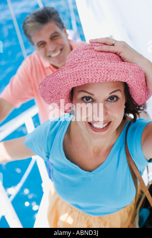 Frau umklammert Hut beim Klettern Treppe Stockfoto