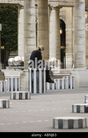 Frau am Handy sitzt auf Skulptur Spalte im Palais Royal Paris France Stockfoto