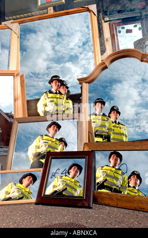 Zwei Polizisten, ein Mann und eine Frau, reflektiert im Spiegel in Schaufenster in Sussex Stockfoto