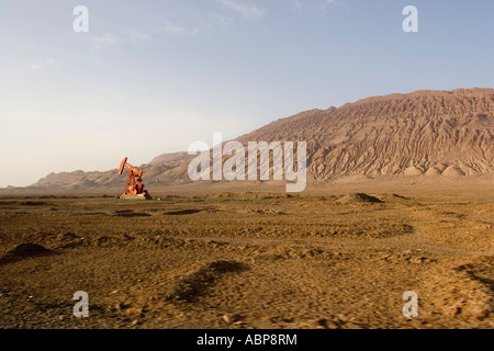 Ein nickend Esel Pumpe Jack oder Pumpstand ist in der Wüste in der Nähe von Turpan in Xinjiang, China, mit Feuer Berg im Hintergrund gesehen. Stockfoto