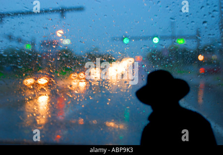 Mann im schwarzen Hut und Regenmantel Schwerverkehr an regnerischen Nacht überqueren Stockfoto