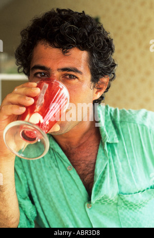 Recife, Brasilien. Unrasiert Mann in ein grünes Hemd, einen rote Milch-Shake aus einem Eisbecher Glas zu trinken. Stockfoto