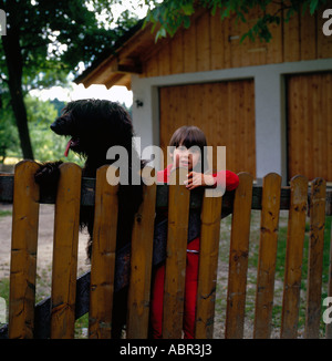 Mädchen und ein schwarzer Französisch Briard Hund hinter Holztor.  Foto: Willy Matheisl Stockfoto