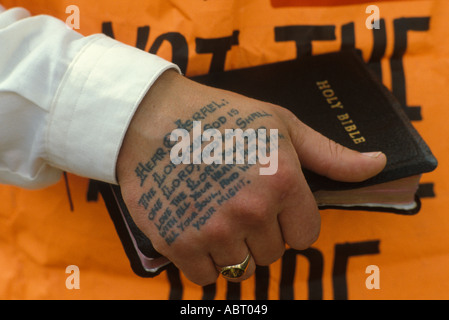 Religiöses Tattoo auf der Hand des Menschen, fanatischer Straßenprediger, hält er eine Bibel Deuteronomy Verse 6:4–5 Glasgow, Schottland Mai 1982. HOMER SYKES AUS DEN 1980ER JAHREN Stockfoto