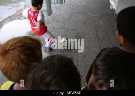 Ein Junge kickt einen Ball während einer Fußball-Club-Sitzung an der Schule, Stoke Newington, London, UK. Stockfoto