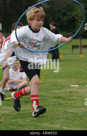 Eine Grundschule junge läuft mit einem Reifen während seiner Schulsporttag Clissold Park, London, UK. Stockfoto