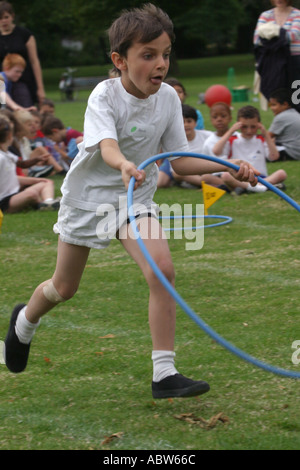 Eine Grundschule junge läuft mit einem Reifen während seiner Schulsporttag Clissold Park, London, UK. Stockfoto