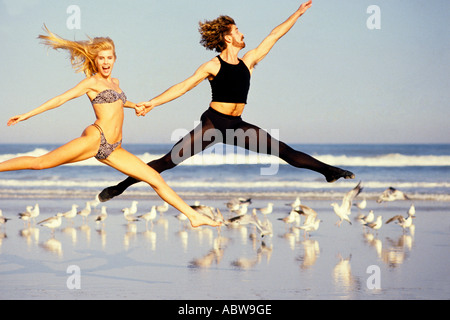 Ballett-Tänzer in anmutigen Pose studieren und Züge für Leistung am Strand praktizieren, wie sie mit Möwen im Hintergrund springen Stockfoto