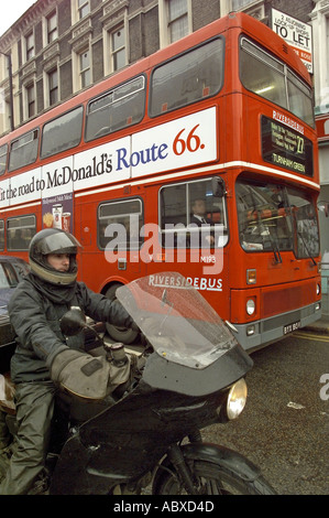 London Transport route 27 Riverside Red Metrobus in Kensington unterwegs für Turnham Green mit Motorradfahrer Vordergrund JMH0382 Stockfoto