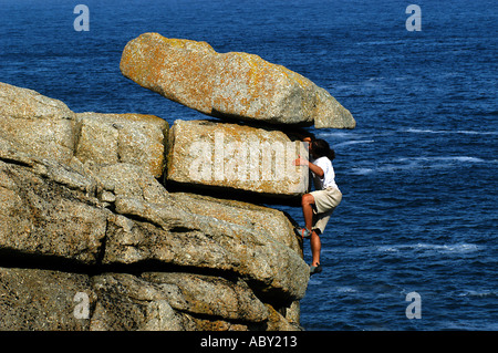 Junger Mann Rock in der Nähe von Sennen Cove, Cornwall, England klettern Stockfoto