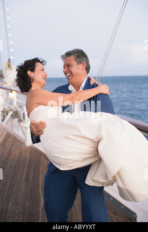 Frisch verheirateten Mann trägt seine Braut auf Bootsdeck Stockfoto