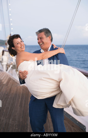 Frisch verheirateten Mann trägt seine Braut auf Bootsdeck Stockfoto