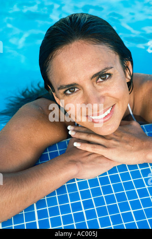 Frau lehnt sich am Rand des Pools Stockfoto