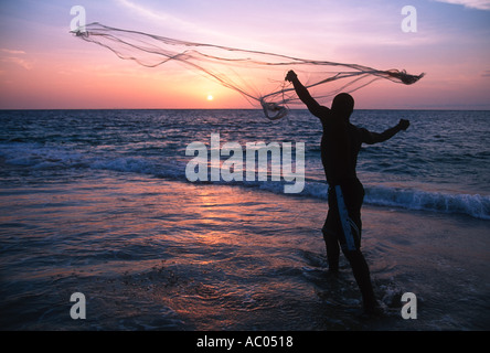 Fischer mit Netz an der Küste bei Sonnenuntergang Gabun gegossen Stockfoto