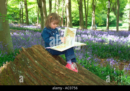 Junge Mädchen lesen Buch in bluebell Holz, norfolk, england Stockfoto