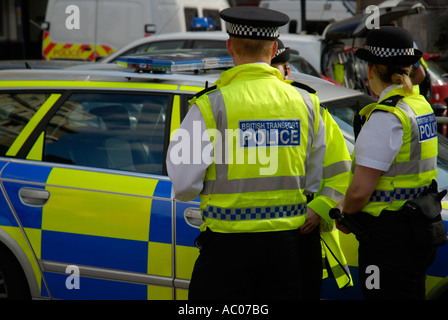 Britischen Transport Polizisten in gelben Jacken stehen neben gelb und blau gefärbten Polizeiauto Stockfoto