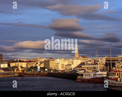 Skyline der Stadt und den alten Hafen im Abendlicht mit Boote festgemacht am Kai und Hallgrimskirkja spire Darüber hinaus. Reykjavik Island Stockfoto