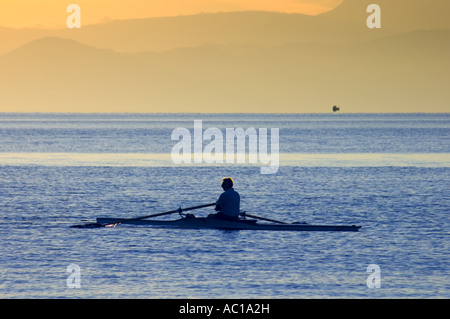 Rudern in den frühen Morgenstunden am Lac Leman, Schweiz, mit den französischen Alpen im Hintergrund. Stockfoto