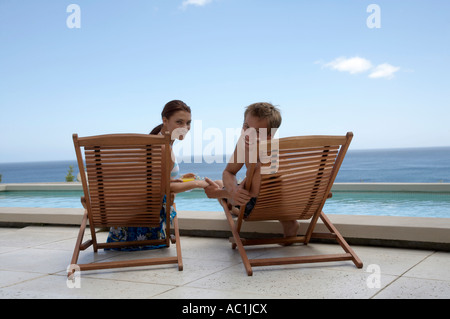 Paar, sitzen in Liegestühlen am Schwimmbad Stockfoto