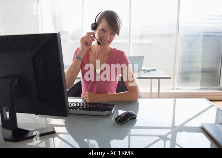 Frau, die Arbeiten am Computer, trägt Kopfhörer Stockfoto