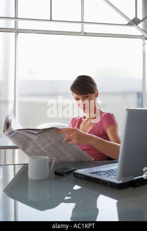 Frau am Schreibtisch lesen Zeitung Stockfoto