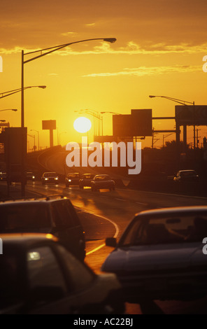 PKW und LKW im täglichen Straßenverkehr pendeln auf gekrümmten i-76 Autobahn bei Sonnenuntergang mit Sonne, Philadelphia PA USA Stockfoto
