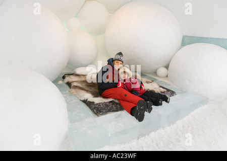 Eine Frau und ein vier Jahre altes Mädchen sitzt auf einem Bett in einem Schlafzimmer von Jukkasjarvi Eishotel Stockfoto