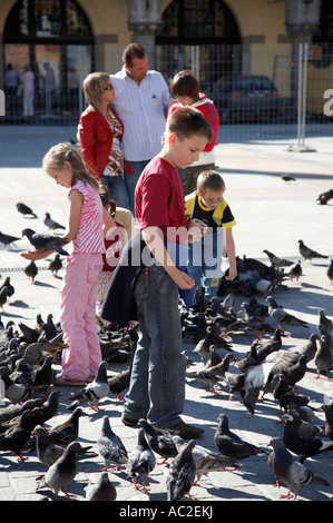 Gruppe von Kindern füttern Tauben im wesentlichen Platz Rynek Glowny Krakau Stockfoto