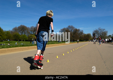 Junger Teenager Inlineskating durch Slalom Kegel im Hyde Park, London, England UK Stockfoto