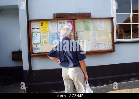 Lokale Bewohner betrachten Gemeinderat Ankündigungen Anzeige im Dorf High Street, Felsted Essex England UK Stockfoto