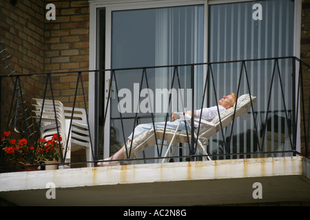 Frau Sonnenbaden auf dem Balkon eines Wohnblocks an der Strandpromenade, Southend on Sea, Essex, England, UK Stockfoto