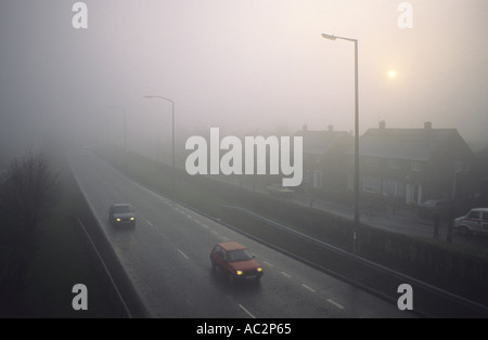 Fahrzeuge fahren auf zweispurigen bei Nebel wie die Sonne beginnt zu brennen durch Nebel Leeds Yorkshire uk Stockfoto