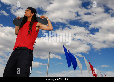 Schwarzen männlichen Skateboarderwith Dreadlocks posieren gegen eine blau bewölktem Himmel und Fahnen Bend Oregon USA Stockfoto