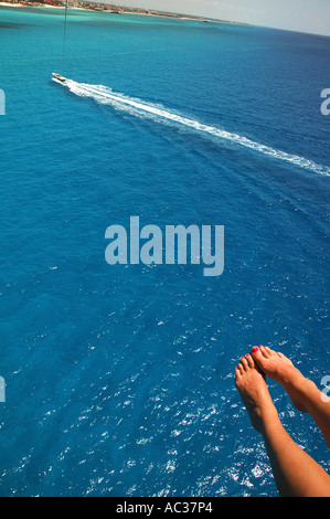 Ein paar Füße stehen im Vordergrund als eine Boot-schleppt ein Parasail als das blaue Wasser des Golf von Mexiko liegen unten vor der Küste Stockfoto