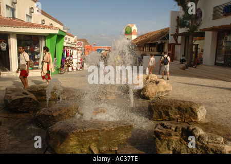 Ein Brunnen sprudelt entlang der Fifth Avenue in Playa del Carmen, Mexiko, wie Touristen vorbeigehen. Stockfoto