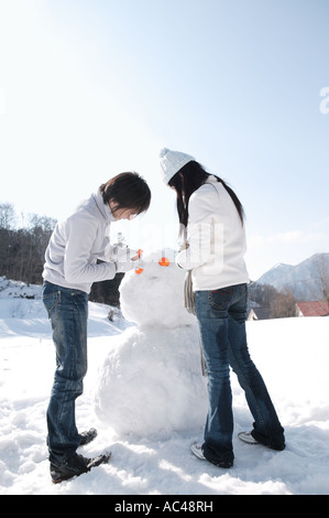 Junges Paar machen Schneemann Stockfoto