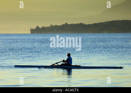 Rudern in den frühen Morgenstunden am Lac Leman, Schweiz, mit den französischen Alpen im Hintergrund. Stockfoto