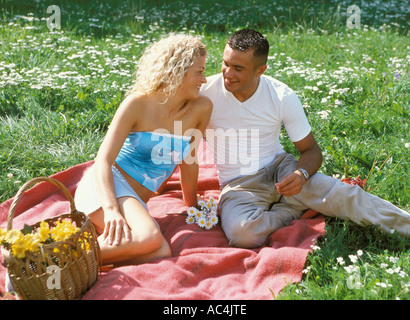 Mann und Frau sitzen auf Decke mit Blumen Stockfoto