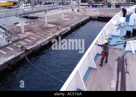 Das Deck des Bootsanlegewerks im Hafen von Ajaccio mit einem Seeleute-Crew-Mitglied, das während des Andockvorgangs zusammen mit Hafenarbeitern einen dünnen, leichten Festnetzanschluss zusammensammelt Stockfoto