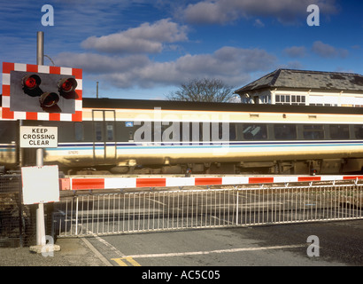 Zug auf der Durchreise ein Bahnübergang in Großbritannien mit der Barriere gesenkt Stockfoto