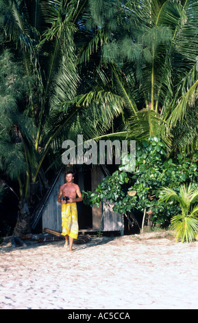 Ein Reisender ergibt sich aus einer Strandhütte, umgeben von Palmen Bäume Tioman Island South China Sea Ostküste Halbinsel Malaysia Stockfoto