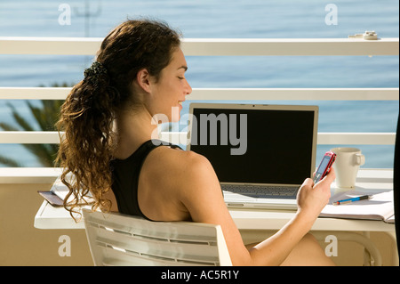 Frau mit Laptop auf dem Balkon mit Blick auf das Meer Stockfoto